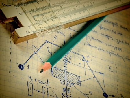 pencil and a slide rule on the old page with the calculations in mechanics