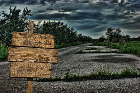 old wooden road sign on a dark deserted road