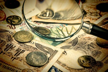magnifying glass on a pile of old European moneyの写真素材