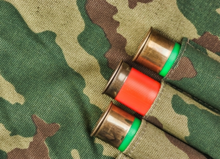 Old hunting cartridges and bandoleer on camouflage background