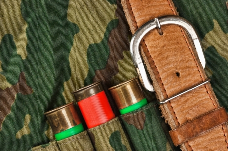 Old hunting cartridges and bandoleer on camouflage background