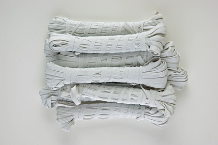 Sewing white rubber on a reel on white backgroundの写真素材