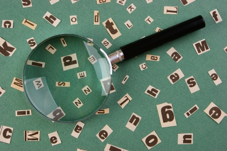 letters cut from newspaper and magnifying glass on green backgroundの写真素材