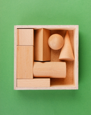 wooden geometric shapes in a box on a green backgroundの写真素材