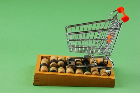 Shopping cart and abacus on the green background