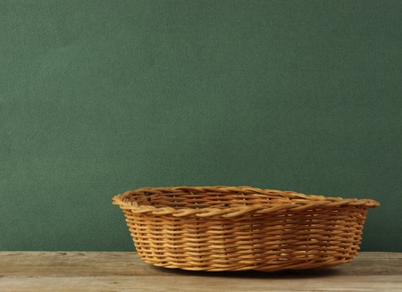 empty wicker basket on an old wooden table  against grunge wallの写真素材