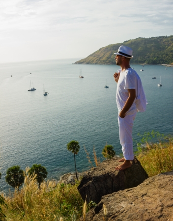 A young man standing on a rock and looking at the sunset of Phuketの写真素材