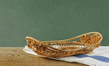 empty wicker basket on an old wooden table against grunge wall