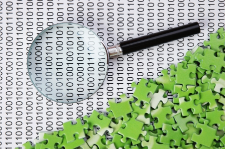 puzzles and magnifying glass on a binary codeの写真素材