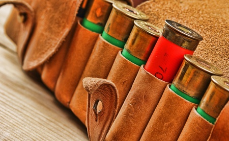 Old hunting cartridges and bandoleer on a wooden table