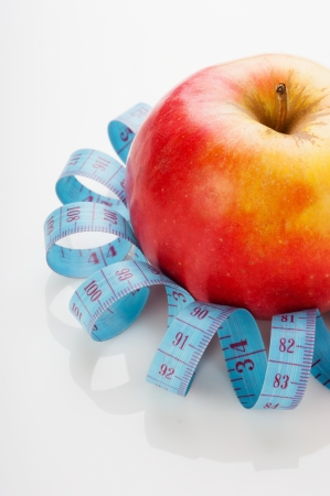 blue measure tape and red apple  on white backgroundの写真素材