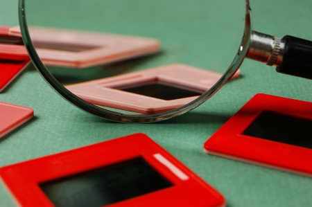 old slides and a magnifying glass on green tableの写真素材