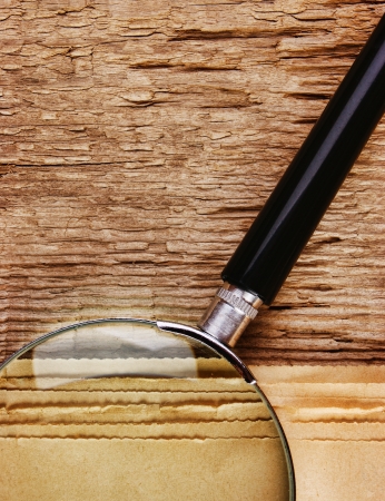 edge of the old newspaper and magnifying glass on a wooden backgroundの写真素材