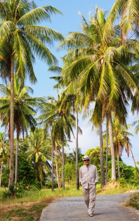 A man walking along the road in palm forestの写真素材