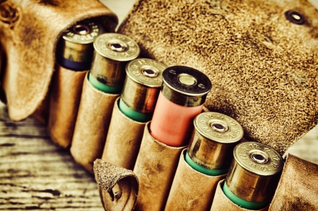 Old hunting cartridges and bandoleer on a wooden tableの写真素材