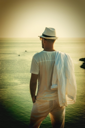 A young man standing on a rock and looking at the sunset of Phuketの写真素材