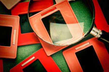 old slides and a magnifying glass on green tableの写真素材