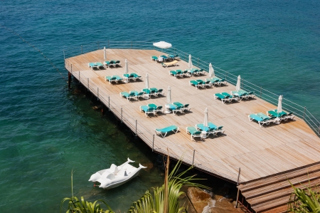 empty chaise-longue on the pier at the seaの写真素材