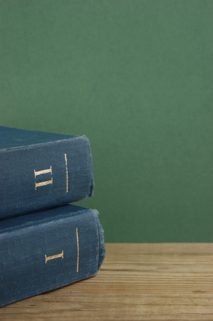Old books on a wooden shelf against a green wallの写真素材