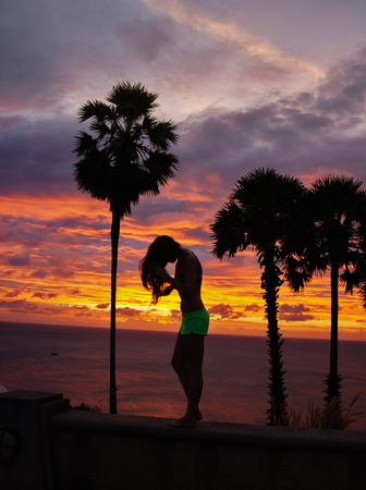 girl silhouette on sunset beach backgroundの写真素材