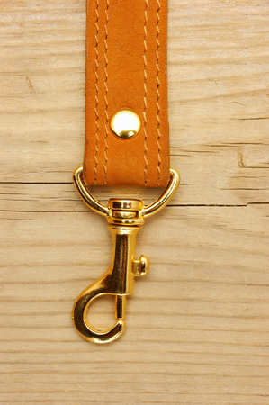 leather strap with carabiner on a wooden boardの写真素材
