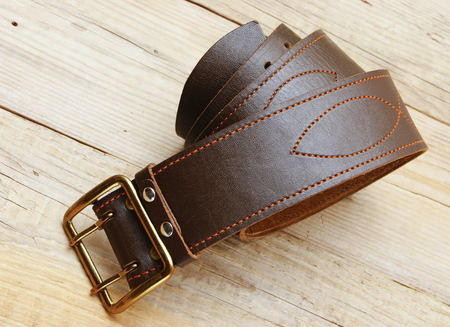 leather belt with a buckle on a wooden boardの写真素材