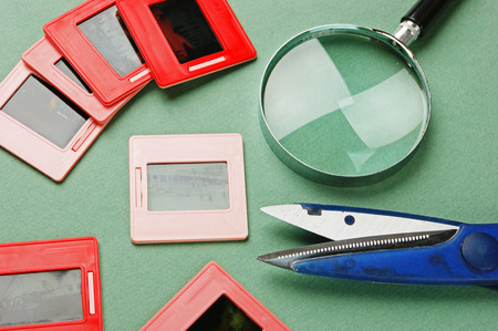 old slides and a magnifying glass on green tableの写真素材