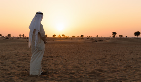 Arab man stands alone in the desert and watching the sunset の写真素材