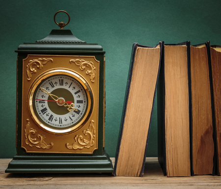 old books on a wooden shelf and watchesの写真素材