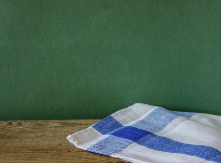 Table-napkin and old wooden deck table with green grunge background