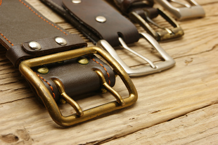 leather belt with a buckle on a wooden boardの写真素材