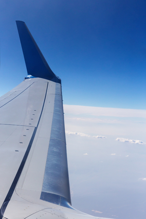 Airplane wing in the blue sky with white cloudsの写真素材