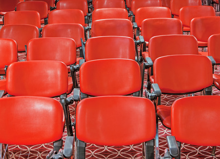 red recliners stand rows in an empty conference hall