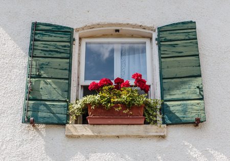 Window in an old house decorated with flower pots and flowersの写真素材