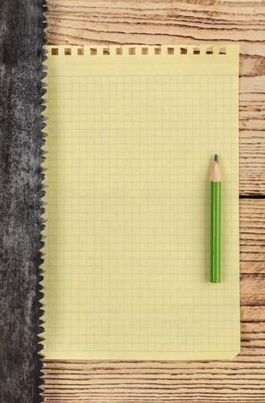 old saw and a piece of notebook on wooden backgroundの写真素材