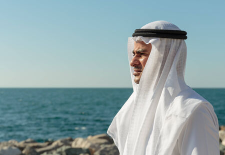 DUBAI, UAE - NOVEMBER 7, 2013: Arabic man is on the waterfront and looking at the seaのeditorial素材