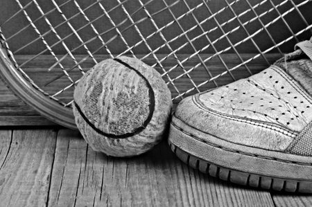 old tennis ball and racket with sneakers on a wooden floorの写真素材