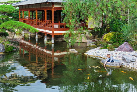 MONTE CARLO, MONACO - NOVEMBER 2, 2014: Japanese garden, girl feeding fish in a pondのeditorial素材