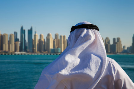 DUBAI, UAE - NOVEMBER 7: Modern buildings in Dubai Marina,, UAE. In the city of artificial channel length of 3 kilometers along the Persian Gulf. Man in Arab dress looks at the cityのeditorial素材