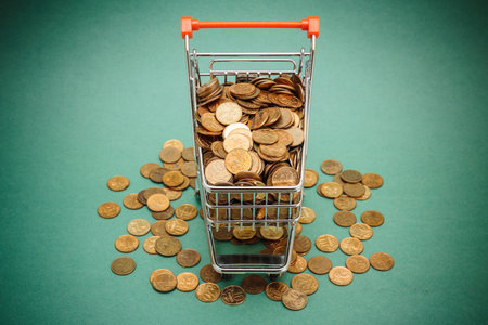 Shopping trolley with coins on a green backgroundの写真素材