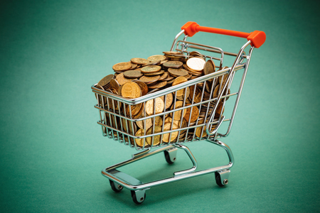 Shopping trolley with coins on a green backgroundの写真素材