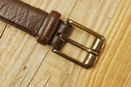 leather belt with a buckle on a wooden board