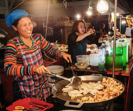 PATTAYA, THAILAND - APRIL 4, 2015: Woman in a street cafe  fry food and smilingのeditorial素材