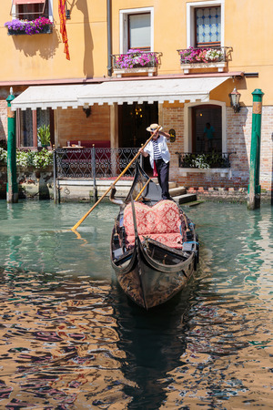 VENICE, ITALY - 26 JUNE, 2014: Gondolier rides gondola. The profession of gondolier is controlled by a guild, which issues a limited number of licensesのeditorial素材