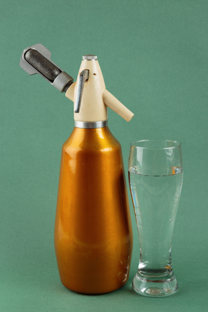 Old vintage siphon and glass of water on a green backgroundの写真素材