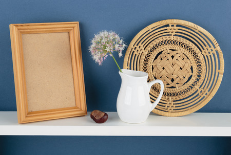 photoframe and vase with a flower on white  shelf on blue wallpaper background