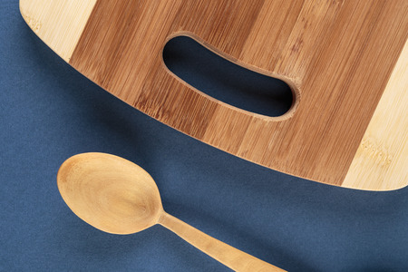 kitchen cutting board and a wooden spoon on a blue backgroundの写真素材