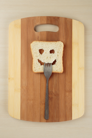 Happy toast with a fork in her mouth on a cutting boardの写真素材