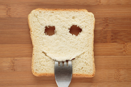 Happy toast with a fork in her mouth on a cutting boardの写真素材