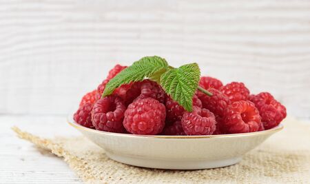 Raspberries in a bowl on a wooden white table